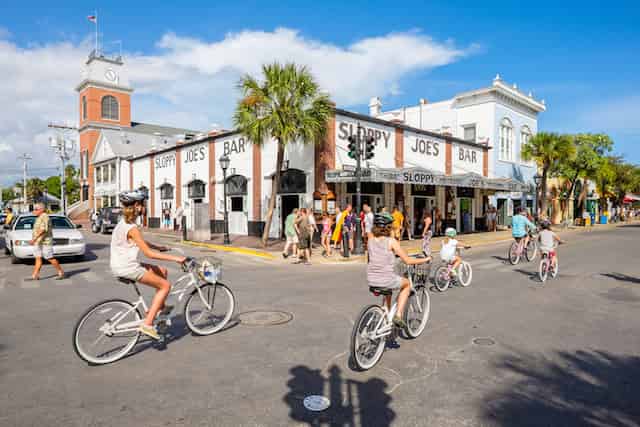 Tourists on bicycles in Key West Florida near the Southernmost Point landmark