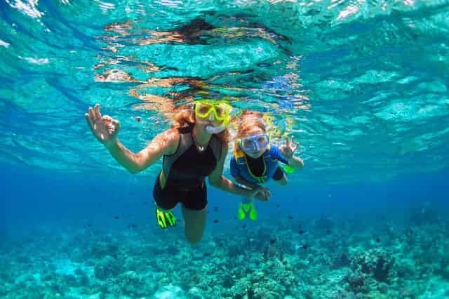 Mother and kid snorkeling underwater